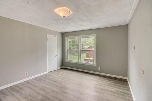 unfurnished room with ornamental molding, a textured ceiling, baseboards, and wood finished floors