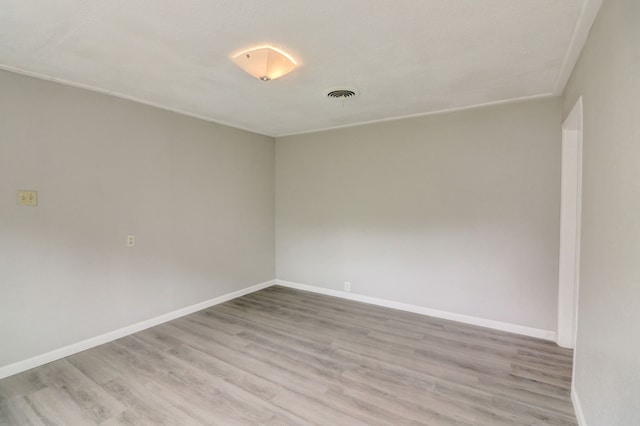 unfurnished room featuring light wood finished floors, visible vents, and baseboards