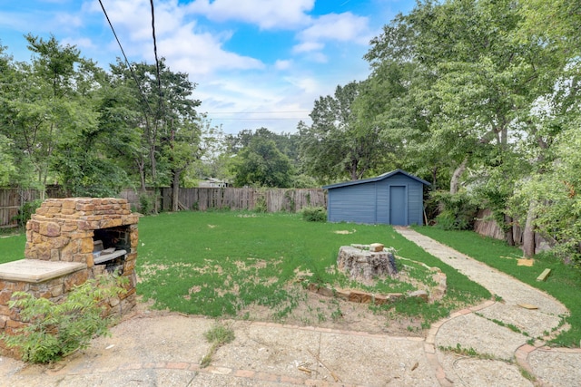 view of yard with an outdoor structure, a fenced backyard, a shed, and an outdoor stone fireplace