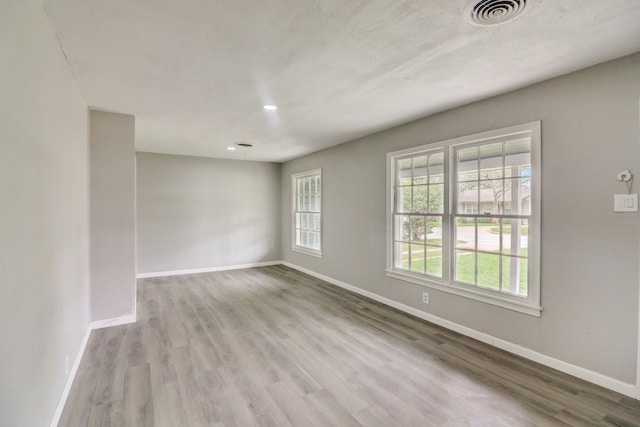 unfurnished room featuring visible vents, baseboards, and wood finished floors