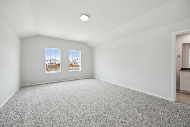 interior space featuring baseboards, lofted ceiling, and light colored carpet