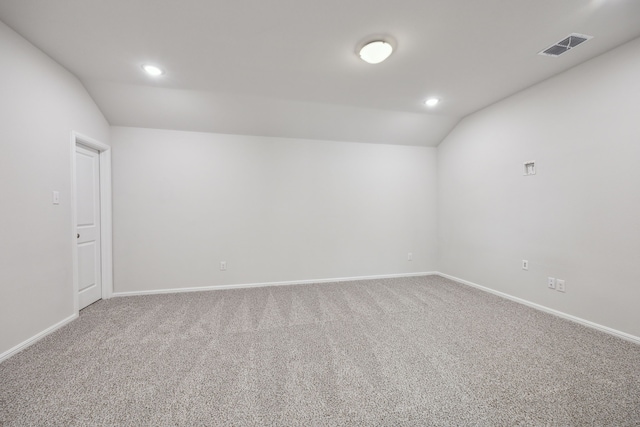 carpeted spare room featuring lofted ceiling, recessed lighting, baseboards, and visible vents