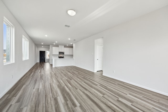 unfurnished living room with recessed lighting, visible vents, light wood-style flooring, and baseboards