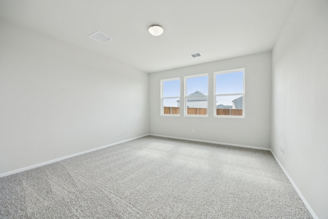 carpeted empty room featuring visible vents and baseboards