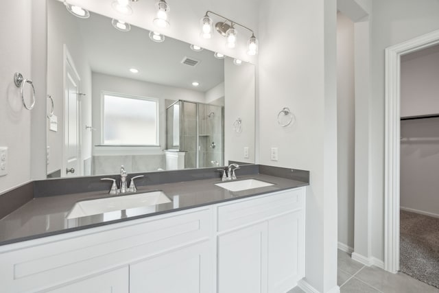 full bath featuring a sink, double vanity, a stall shower, and tile patterned floors