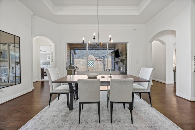 dining room featuring a tray ceiling, arched walkways, and dark wood-style flooring