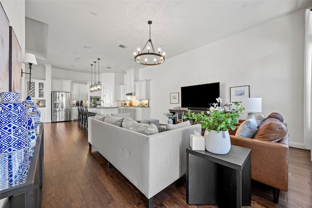 living area with visible vents, a notable chandelier, and dark wood finished floors