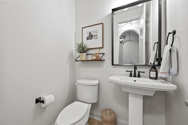 bathroom with baseboards and toilet