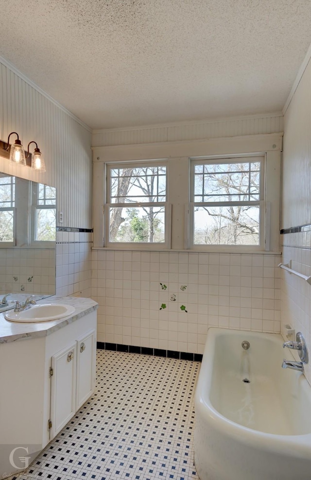 bathroom with vanity, tile walls, a bath, and a textured ceiling