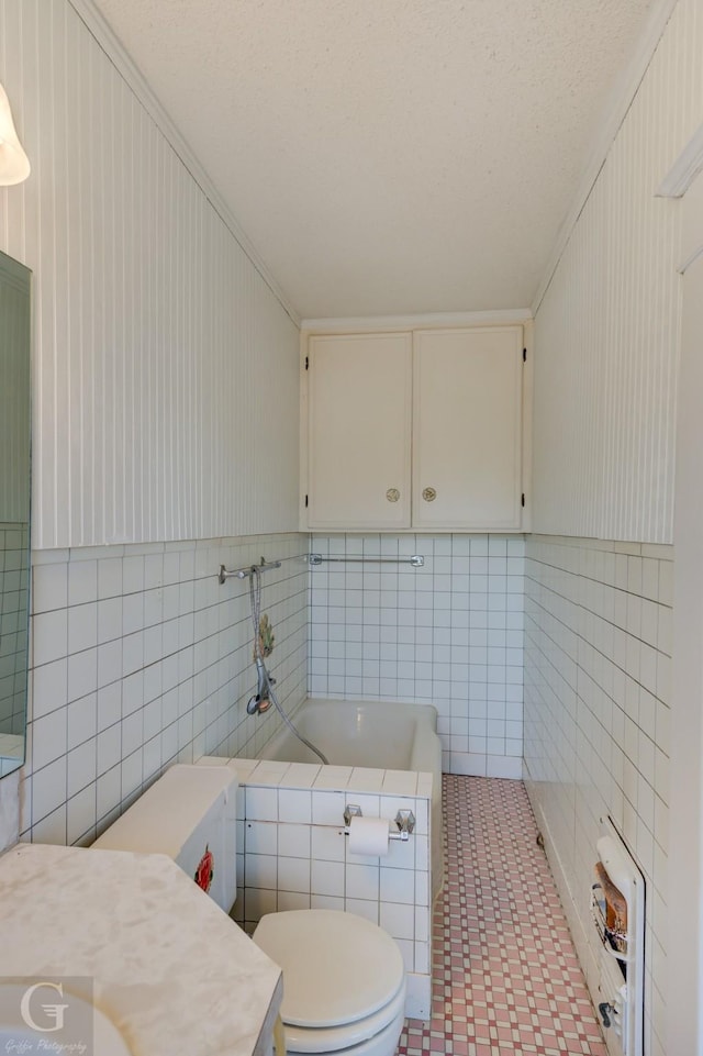 bathroom with tile walls, toilet, and a bath