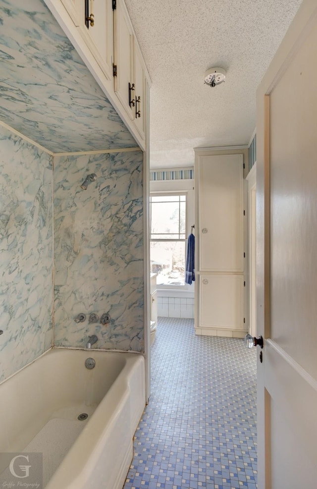 bathroom with a tub to relax in and a textured ceiling