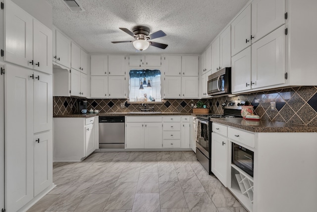 kitchen with dark countertops, visible vents, appliances with stainless steel finishes, marble finish floor, and a sink