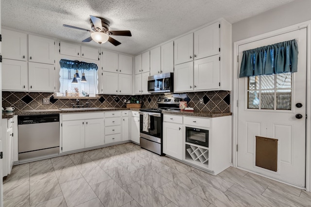 kitchen with dark countertops, marble finish floor, white cabinetry, and stainless steel appliances