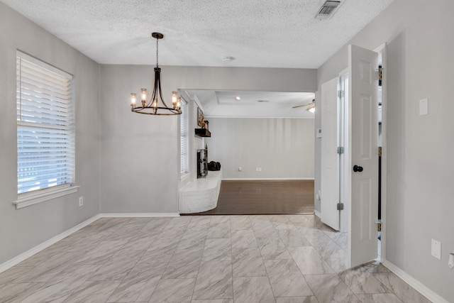 unfurnished dining area with visible vents, marble finish floor, a textured ceiling, and baseboards