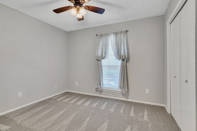 unfurnished room with baseboards, carpet, a ceiling fan, and a textured ceiling