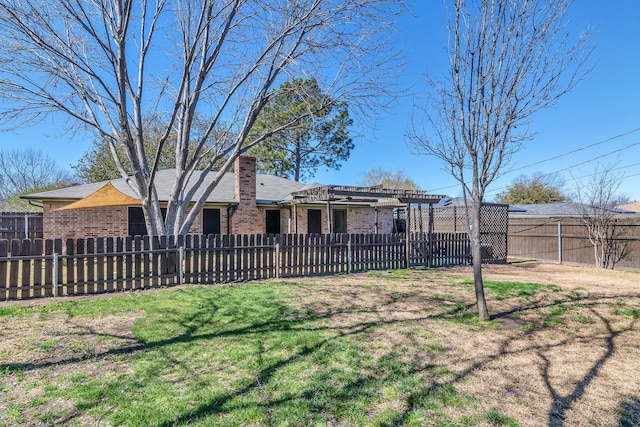 back of house with a pergola, brick siding, a fenced front yard, and a chimney