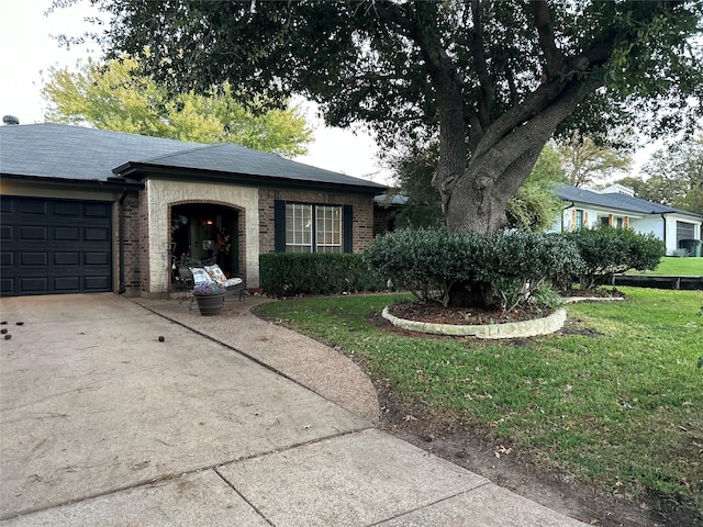 ranch-style home with a front lawn, roof with shingles, concrete driveway, an attached garage, and brick siding