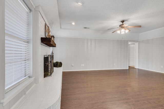 living area with a fireplace, a textured ceiling, a ceiling fan, and wood finished floors