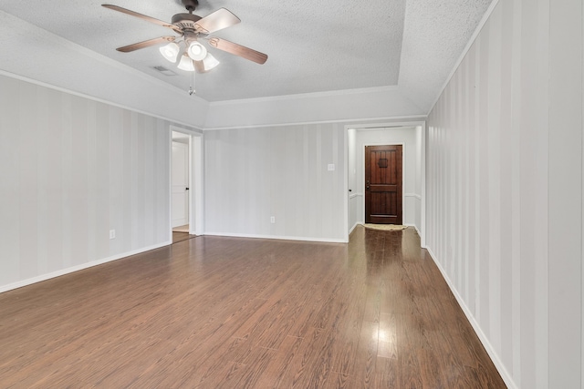 empty room featuring visible vents, ceiling fan, dark wood finished floors, ornamental molding, and a textured ceiling