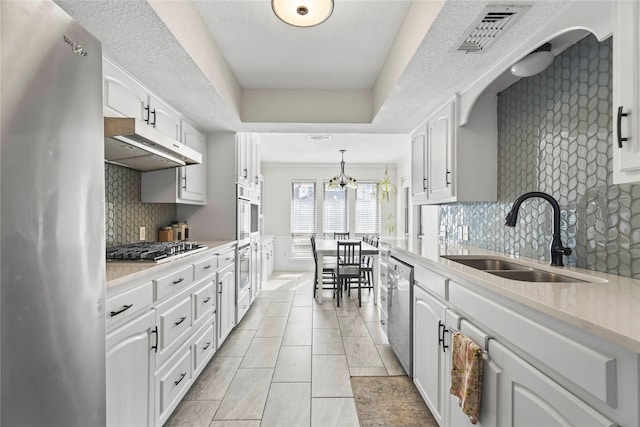 kitchen with visible vents, a sink, under cabinet range hood, stainless steel appliances, and a raised ceiling