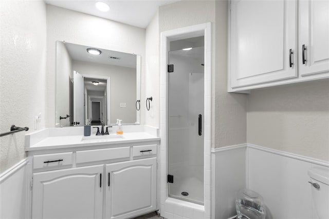 full bathroom with vanity, a shower stall, toilet, and a textured wall