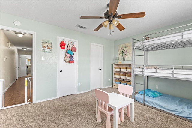 bedroom with visible vents, a textured ceiling, carpet, baseboards, and ceiling fan