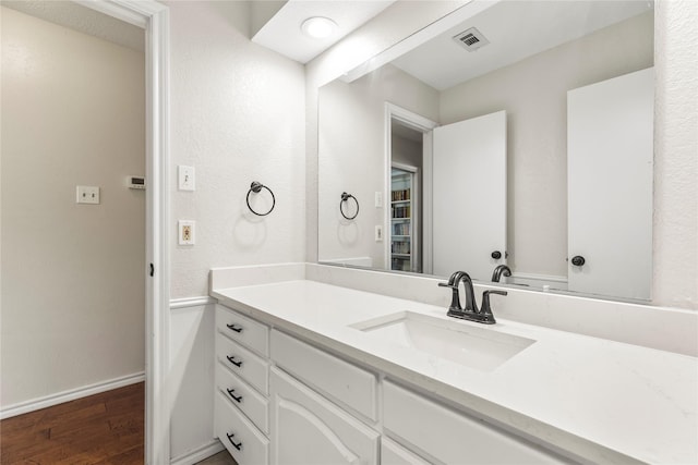 bathroom featuring visible vents, baseboards, wood finished floors, and vanity