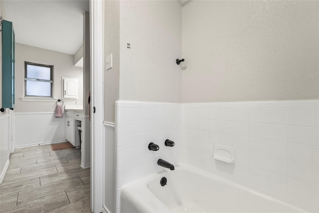 bathroom featuring wood finish floors, a garden tub, and a textured wall