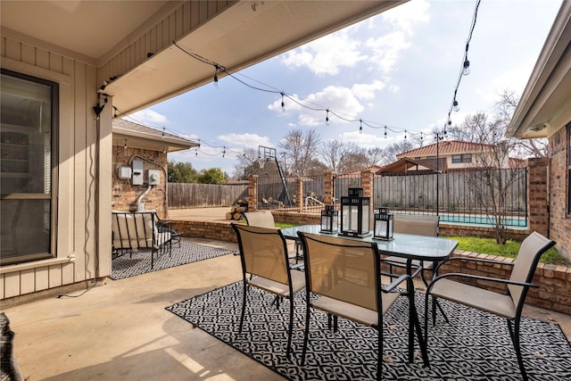 view of patio with a swimming pool, outdoor dining area, and a fenced backyard