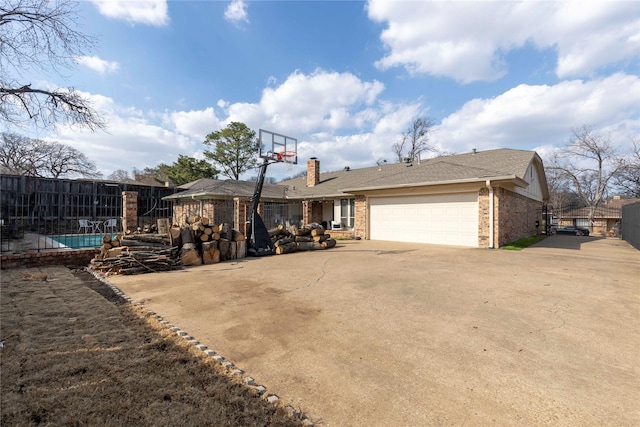 exterior space featuring a garage, brick siding, driveway, and fence