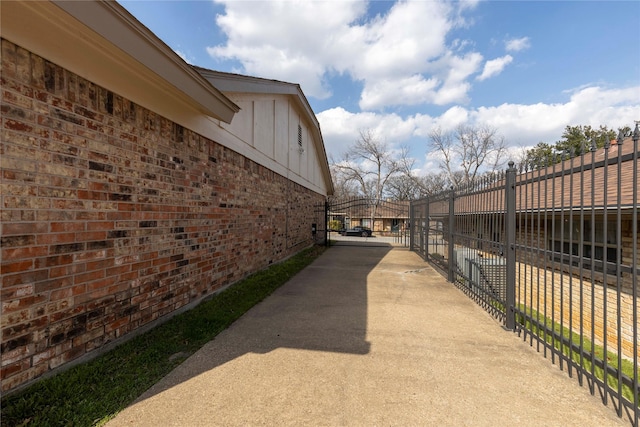 view of property exterior with fence, brick siding, concrete driveway, and a gate