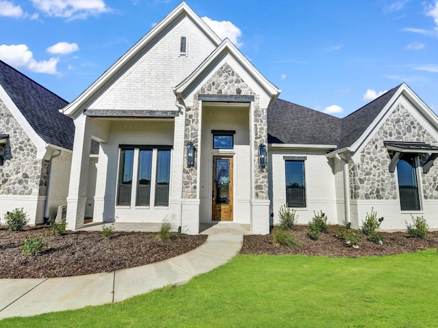 view of front of home with brick siding, stone siding, and a front yard