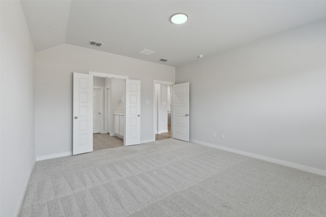 unfurnished bedroom with visible vents, baseboards, light colored carpet, and vaulted ceiling