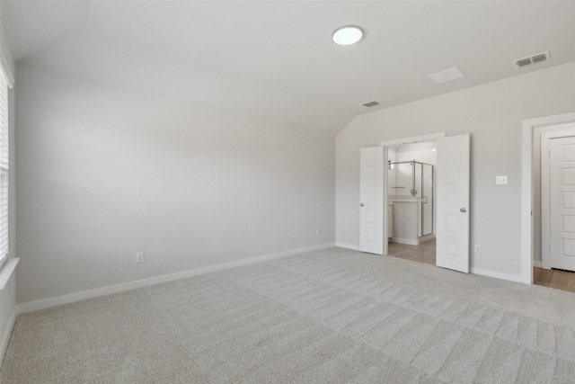 unfurnished bedroom featuring baseboards, visible vents, light carpet, and lofted ceiling