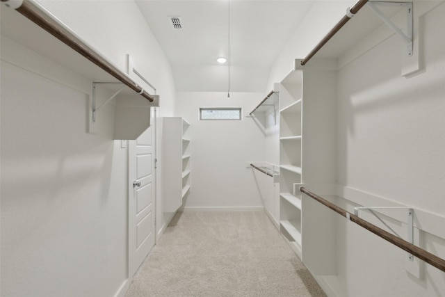 walk in closet with light colored carpet and attic access