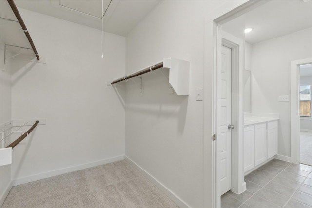 walk in closet with light colored carpet and attic access