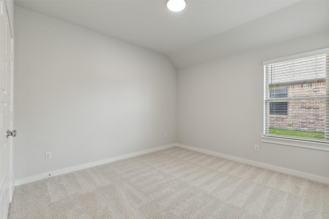 spare room featuring vaulted ceiling, carpet, and baseboards