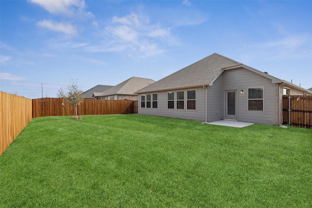 rear view of property with a yard, a patio, a fenced backyard, and a shingled roof