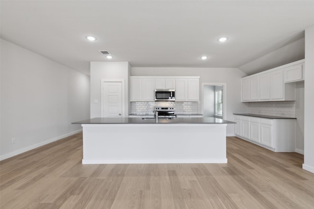 kitchen with visible vents, stainless steel appliances, white cabinets, light wood-style floors, and dark countertops