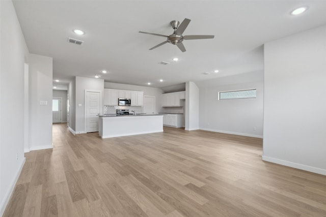 unfurnished living room featuring visible vents, a wealth of natural light, and light wood-type flooring