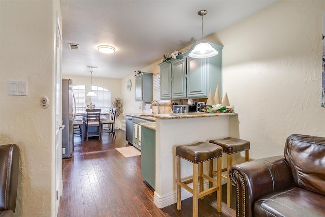 kitchen with a breakfast bar area, dark wood-style floors, visible vents, a peninsula, and appliances with stainless steel finishes