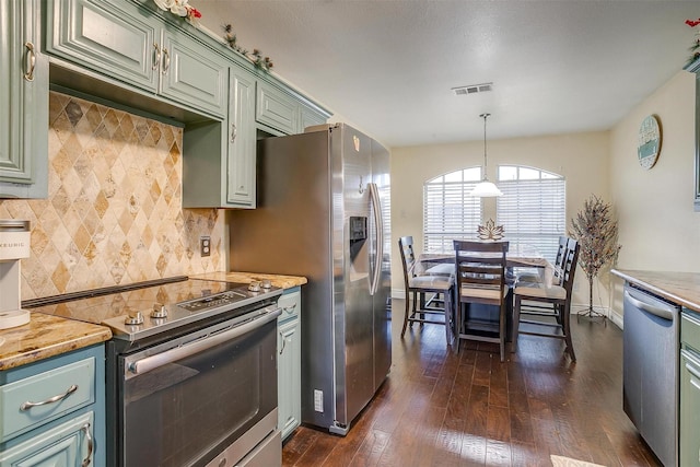 kitchen featuring visible vents, backsplash, stainless steel appliances, dark wood-style flooring, and hanging light fixtures