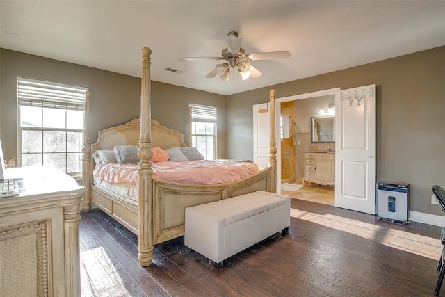 bedroom featuring heating unit, ensuite bathroom, dark wood-type flooring, and a ceiling fan