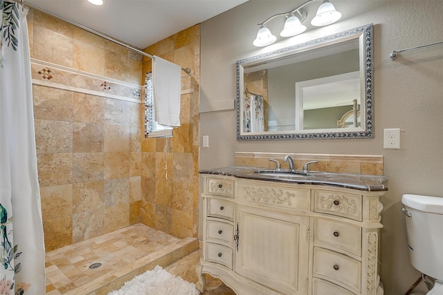 bathroom featuring toilet, vanity, and a tile shower