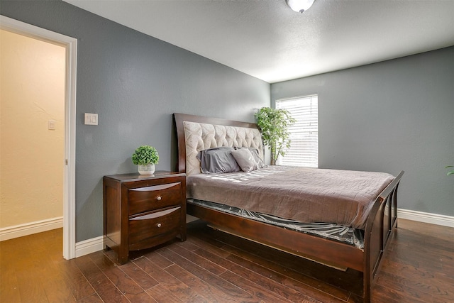 bedroom featuring baseboards and dark wood-style flooring