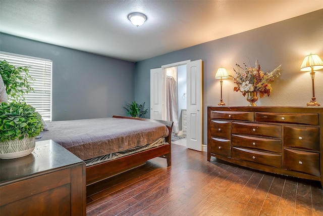 bedroom with dark wood-style floors and ensuite bathroom