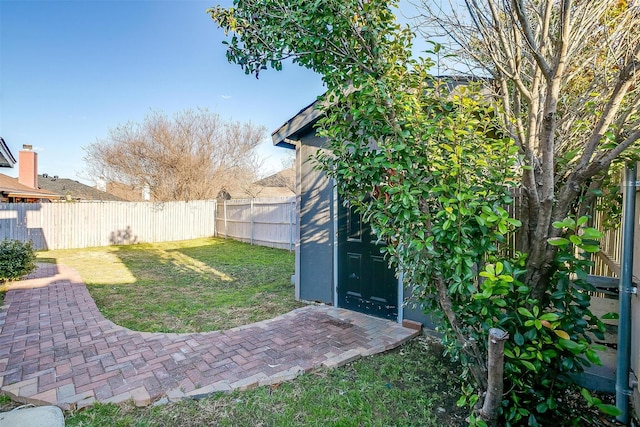 view of yard featuring an outbuilding, a fenced backyard, and a storage shed