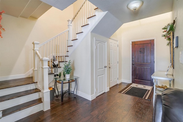 foyer featuring stairway, baseboards, wood finished floors, and vaulted ceiling