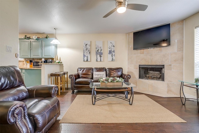 living room featuring ceiling fan, dark wood finished floors, and a fireplace