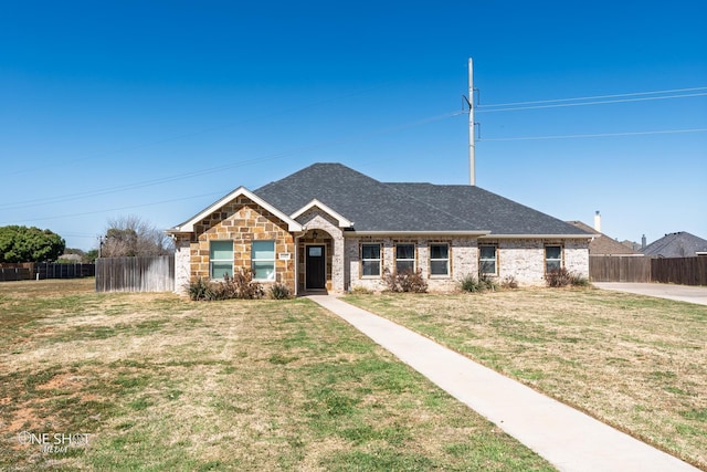 view of front of house with a front lawn, fence, and a shingled roof